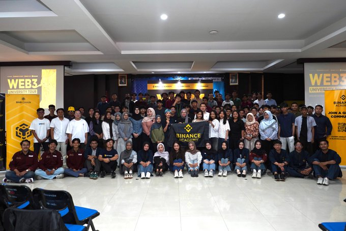 A group photo from the Binance Academy University Tour at Universitas Negeri Surabaya, featuring students and staff posing together with a "Binance Academy" banner, flanked by "WEB3 University Tour" signage that highlights Binance's initiative to introduce students to Web3 and blockchain career opportunities.