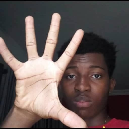 A young person shows their open palm to the camera, with five fingers spread wide in front of their face.