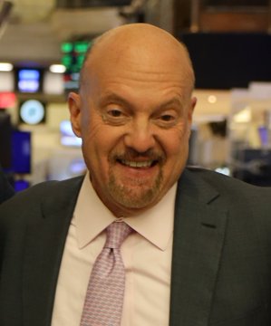 A bald man with a goatee, dressed in a dark suit, white shirt, and patterned tie, smiles broadly at the camera. The image accompanies news of Jim Cramer's bullish recommendation to buy Bitcoin, suggesting he may be the person pictured.