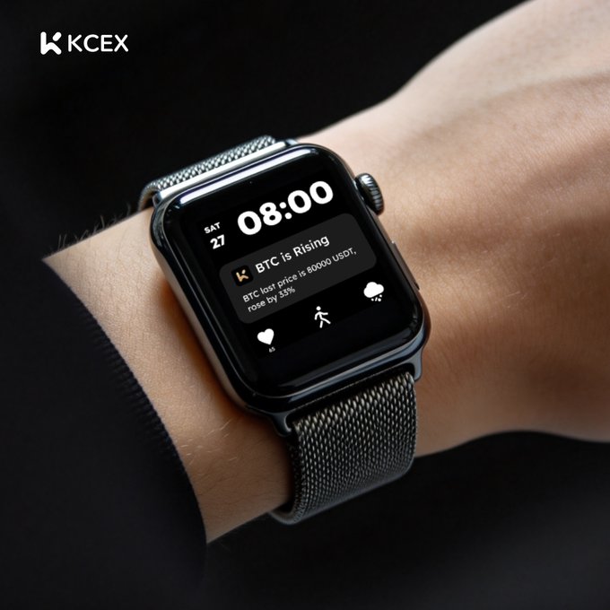 A black smartwatch displays "08:00 SAT 27" with a notification reading "BTC is Rising - BTC last price is 60000 USDT, rose by 33%," fitting the post's "when we back to 80K?" sentiment about Bitcoin's price recovery. The KCEX logo appears in the top-left corner, tying the image to the crypto exchange's optimistic GM greeting.