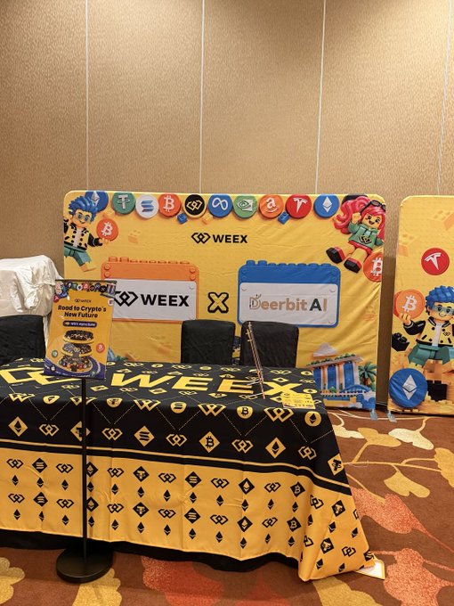 A WEEX crypto event booth features branded banners, cryptocurrency logos, and a display promoting a Road to Crypto's New Future campaign with DeerBit.AI.