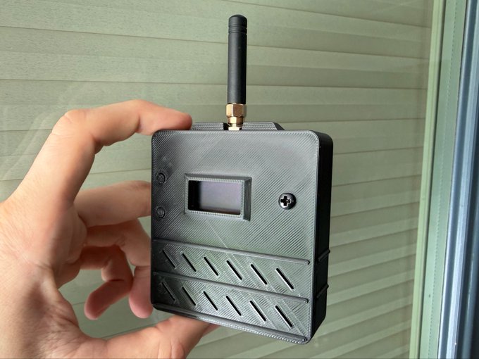 The image shows a hand holding up an electronic device with a black antenna attached to it. The device appears to be a small radio or communication device, possibly used for receiving signals from other devices. It seems that the person is preparing to ship out these devices by Monday, as indicated in the accompanying post.