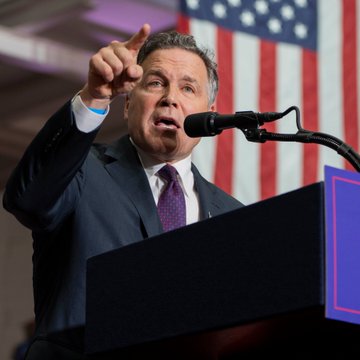 Sen. Dave McCormick (R-PA) speaks passionately at a podium with a backdrop of American flags, gesturing emphatically as he advocates for bringing the CLARITY Act to the Senate floor for a vote on U.S. crypto market structure.