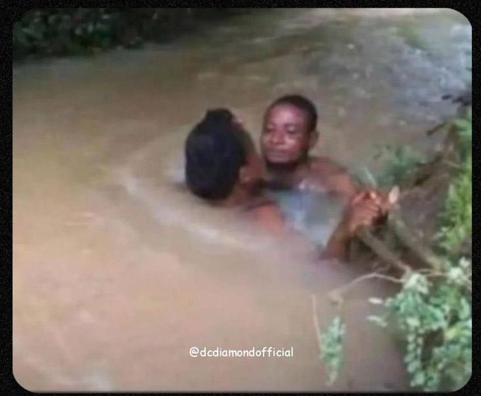 A low-quality video still showing two people in muddy water, watermarked '@dcdiamondofficial'.