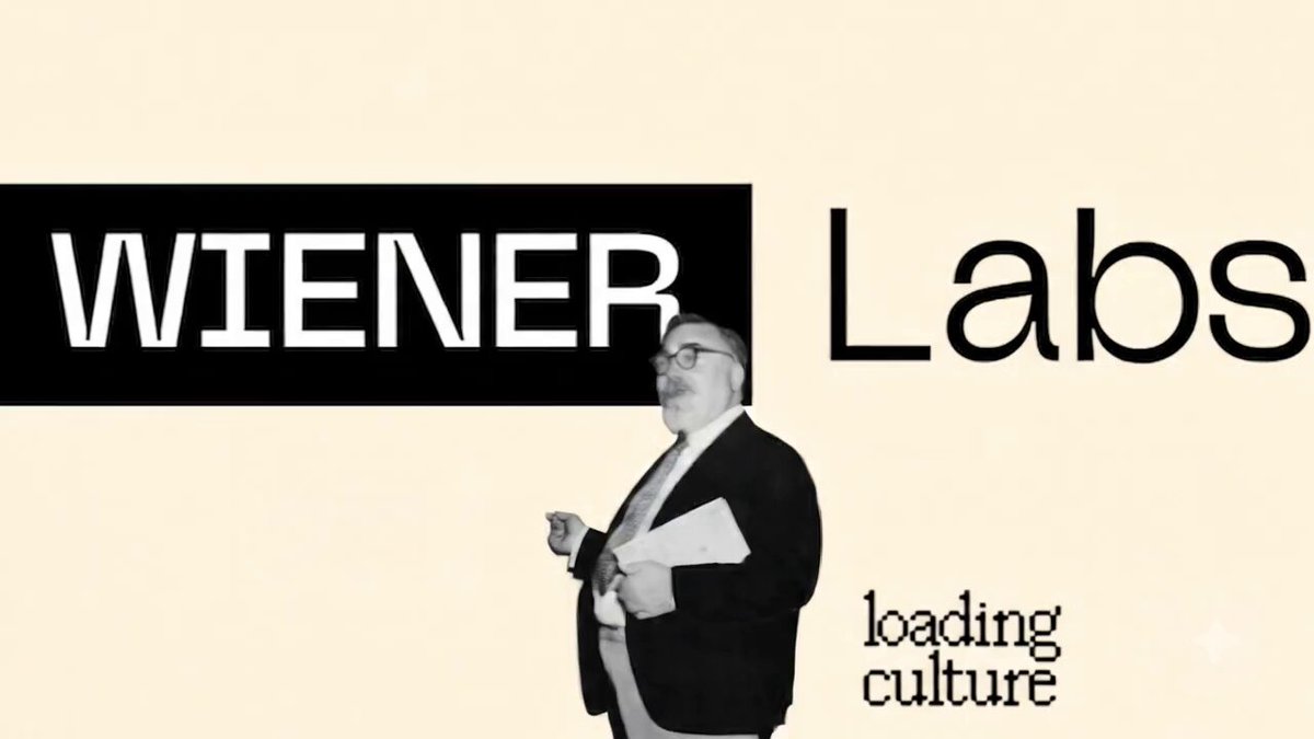 The image features a man dressed in a suit standing next to a sign that says "Winer Labs" written in black text against a white background. The man appears to be talking or giving instructions, possibly related to the concept of "loading culture".