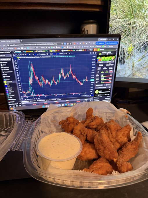 A takeout container of fried chicken tenders with a cup of dipping sauce sits in front of a laptop displaying a TradingView chart with a "TENDIES" logo visible. The image plays on the trader slang "$TENDIES" (referring to profits), showing actual chicken tenders alongside the trading screen as the user humorously tracks the price of chicken tenders until they surpass the stock's price.