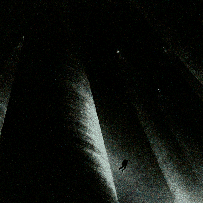 A dark, moody illustration shows a small silhouetted figure floating or falling through a vast black space pierced by several beams of pale light.