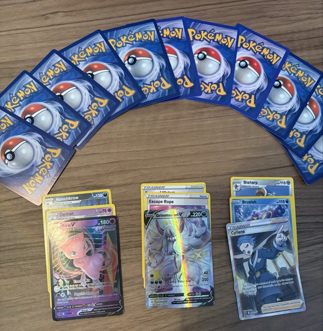 A fan of Pokémon TCG cards displays a fan-arranged row of ten face-down Pokémon card backs on a wooden surface, alongside three revealed cards featuring Honchkrow, Joltik/Mew, and Grimsnarl with Bisharp, Bruxish, and Cynthia trainer cards. The scene supports the post's theme of a new gacha system on Jupiter Exchange by showcasing collectible, blockchain-ready Pokémon cards ready for a digital asset reveal.