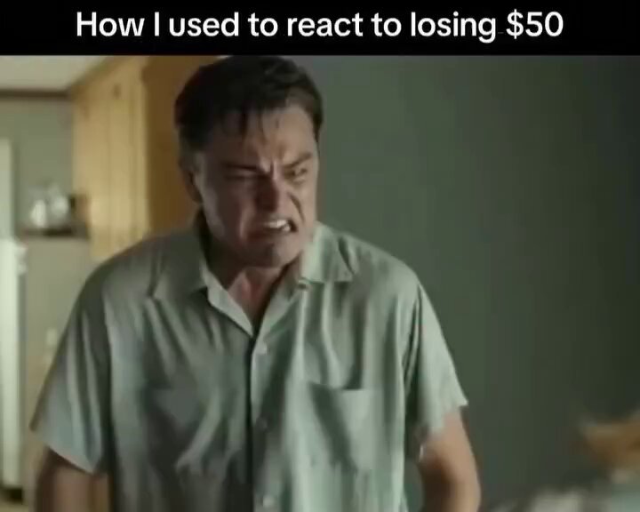 The image features a man standing against a gray wall, wearing a green shirt and staring at something or someone off camera. The caption of an internet meme below this image states "How i used to react to losing $50 vs me losing $$#". It seems that the image is being used as part of a humorous caption for a post about finances or budgeting challenges.
