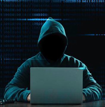 A hooded figure obscured in shadow sits at a laptop with blue digital code streams cascading in the background.