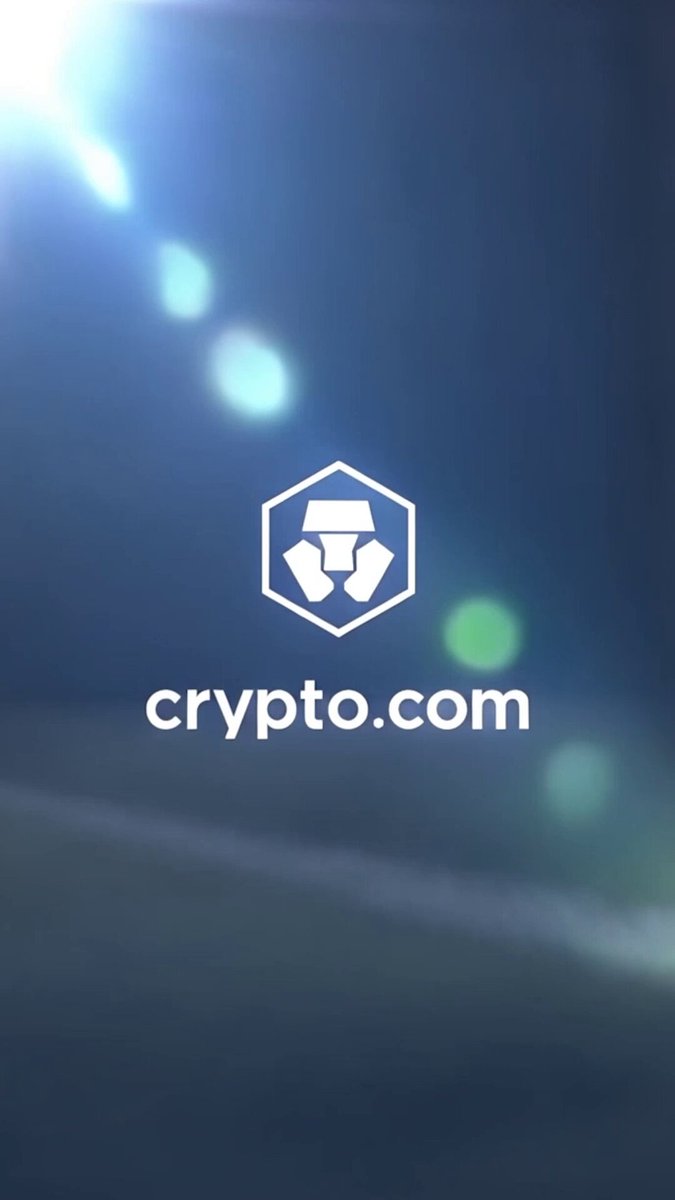 The image features a poster with a logo for Crypto.com that includes a white hexagon with a blue center, surrounded by green circles. The background of the poster is dark blue, creating a contrast with the white elements. The text on the poster reads "What an experience we had at the Brazil vs. Haiti match! A true display of the passion that moves the world." This message highlights the excitement and energy surrounding the Crypto.com platform, which aims to connect people who are passionate about cryptocurrency.