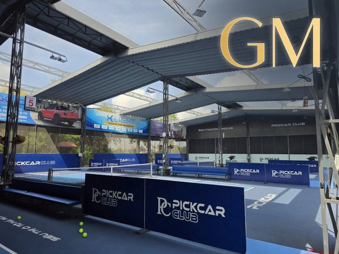 Covered paddle tennis court facility branded with 'PICKCAR CLUB' and 'X-LIGHT' signage, with 'GM' displayed in large gold letters.