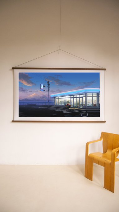 A framed photograph of a twilight gas station hangs on a minimalist gallery wall above a wooden chair, marking the artist's launch of new work reserved by collectors after months of preparation.