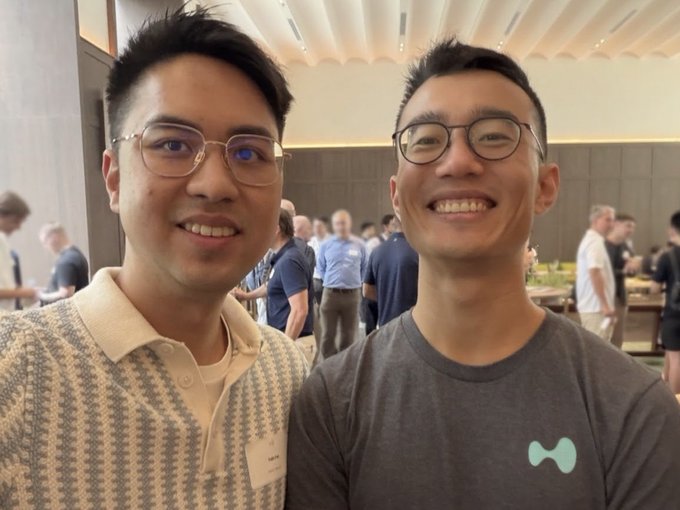 Two smiling men pose together at what appears to be a Hyperliquid ecosystem event, with one wearing a patterned polo shirt and the other sporting a gray t-shirt featuring the distinctive Hyperliquid "H" logo, matching the caption about meeting Jeff at an HL event and celebrating their integration into the ecosystem.