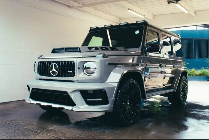A silver Mercedes-Benz G-Wagon SUV parked in a garage or detailing shop with black alloy wheels.