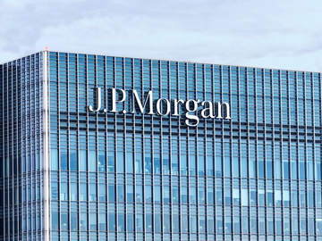 The image shows the exterior of a JPMorgan office building, with the company's name "J.P.Morgan" displayed in large silver lettering across the glass facade. The image visually represents JPMorgan as the institution issuing the warning about Bitcoin's structural risks related to private blockchain networks.