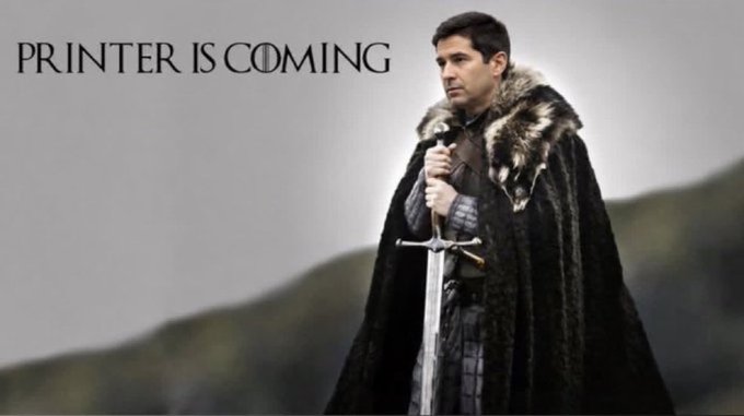 The image parodies the "Winter is Coming" slogan from Game of Thrones, showing a man in a fur-lined cloak holding a sword with the text "PRINTER IS COMING," referencing concerns about currency devaluation as justification for holding Bitcoin. The meme humorously frames the looming threat of central bank money printing as a coming storm that makes Bitcoin a necessary hedge.