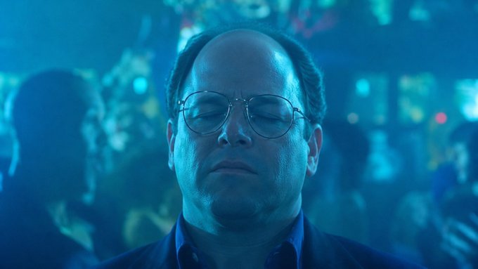 A cinematic close-up of actor Paul Giamatti as Barney Ross from 'The Hangover' with his eyes closed, illuminated by teal-blue lighting in a crowded club setting.