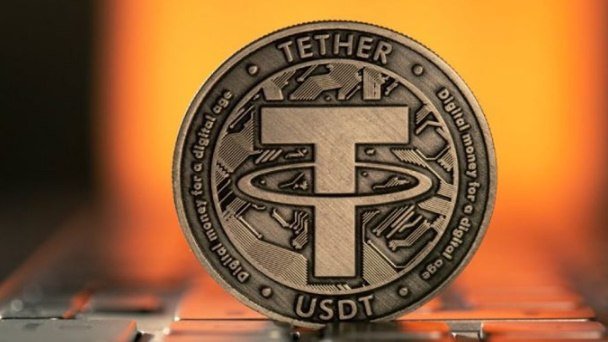 A close-up of a metallic Tether (USDT) cryptocurrency coin with 'TETHER' and 'USDT' inscribed, surrounded by the phrase 'Digital money for a digital age.'