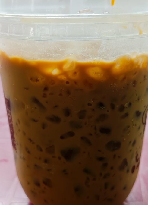 A close-up of an iced coffee in a clear plastic cup, with cream swirling through the rich brown liquid. The drink ties in perfectly with the post's weekend message about unwinding with a leisurely cup of coffee and a relaxed breakfast before tackling the grind.