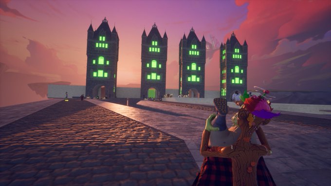 A video game character stands on a cobblestone path looking toward four tall, gothic towers with glowing green windows set against a pink and purple sunset sky.
