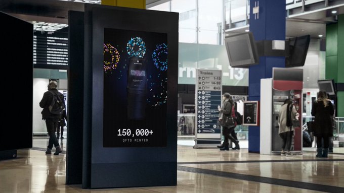 An airport or transit hub scene featuring a large digital display showing watches and the text '150,000+ OPTO MINTED', with travelers and a 'Trains 1-13' sign visible in the background.