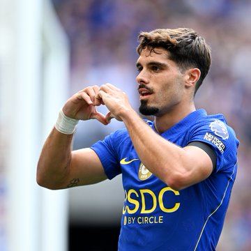 A Chelsea FC player in the team's blue jersey featuring the "SDC powered by Circle" sponsor logo makes a heart shape with his hands, celebrating with the fans after scoring, matching the blue heart emoji.