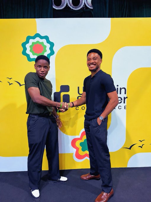 Two men smile and shake hands on stage in front of a bright yellow backdrop featuring colorful flower graphics and partial "Y" lettering, with the caption "Gm Ct While you are sleeping, @NiphermeDave is about to change my life with deals" celebrating the partnership moment captured.