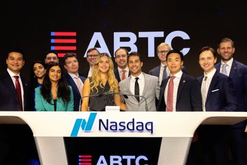 A group of professionally dressed people standing at the Nasdaq podium with 'ABTC' displayed on the screen behind them, likely at a stock listing ceremony.