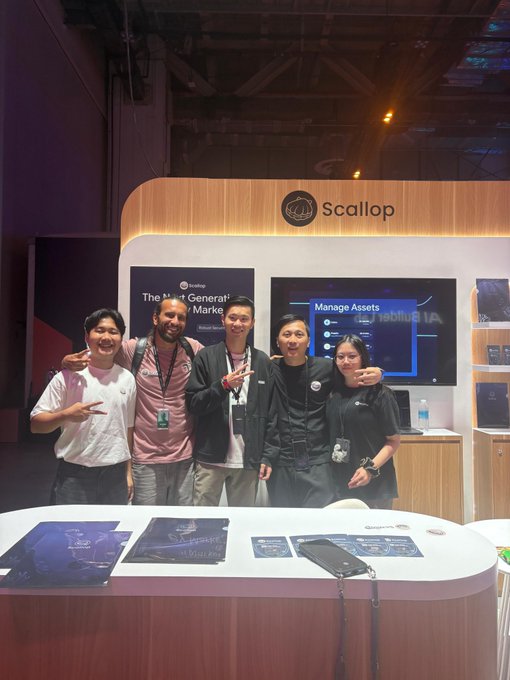 Five people posing together at a 'Scallop' exhibition booth, with displays reading 'The Most Generative Market' and 'Manage Assets'.