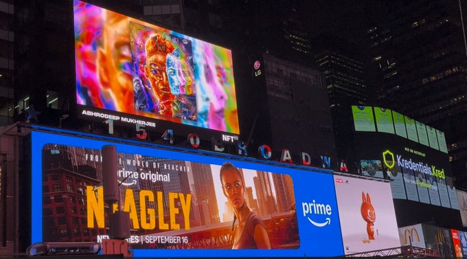 The image showcases "Prismatic Awakening," an NFT artwork by Abhrosee Mukherjee, displayed on a large digital billboard at Times Square in New York City. Below the artwork, prominent advertisements for "The Peripheral" (a Prime Original series releasing September 16) and Keerdentials are visible, highlighting the vibrant commercial atmosphere surrounding the NFT display during NFT_NYC.