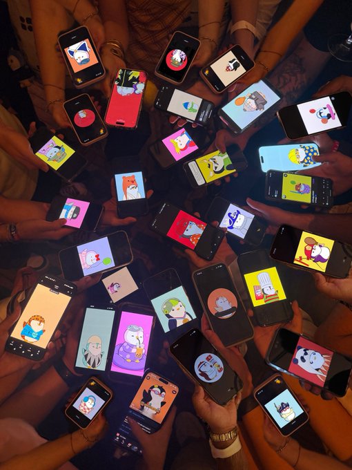 Multiple hands hold smartphones arranged in a circle, each displaying various colorful cartoon avatars or characters on their screens.