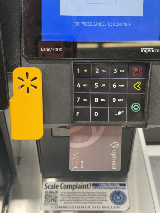 A Uphold Visa debit card is inserted into a self-checkout machine at Lane/7000. This relates to the post by showing a physical transaction potentially using funds from the Uphold platform, which is associated with XRP.