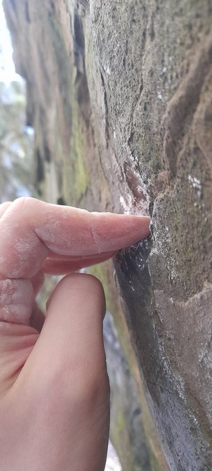 A hand pinches a thin edge of a rock in an extreme grip, humorously illustrating the "razor thin" state of $BBBYQ stock, with no visible text or numerical figures in the image itself.