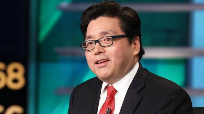 A man in a dark suit, red tie, and black glasses appears on a financial news program with the partial "S&P 500" logo visible behind him. The image relates to the post as Tom Lee, a well-known market analyst, is shown commenting on Korean stock market volatility potentially affecting cryptocurrency markets through margin liquidations.