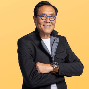 Robert Kiyosaki, author of "Rich Dad Poor Dad," smiles confidently with arms crossed, wearing blue-rimmed glasses and a dark blazer—visually reinforcing his financial advice to invest in appreciating assets like Bitcoin rather than holding weakening cash.
