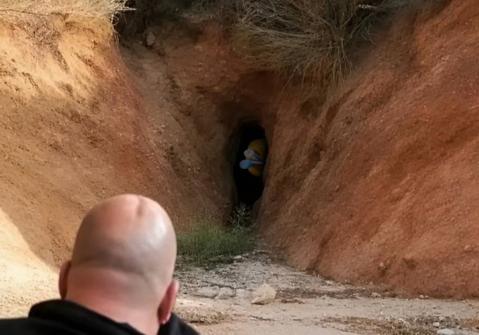 The image shows a person looking into a dark tunnel in a dirt embankment, where a figure resembling Homer Simpson is visible. The post title "there it is, LMAO!" likely refers to the humorous discovery of the character in an unexpected location.