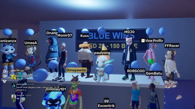 A screenshot from a virtual reality game showing various cartoonish avatars gathered around a stage labeled 'BLUE WINS' after a competition, with usernames like Monir07, MOJO, and jtm0ney101 visible.