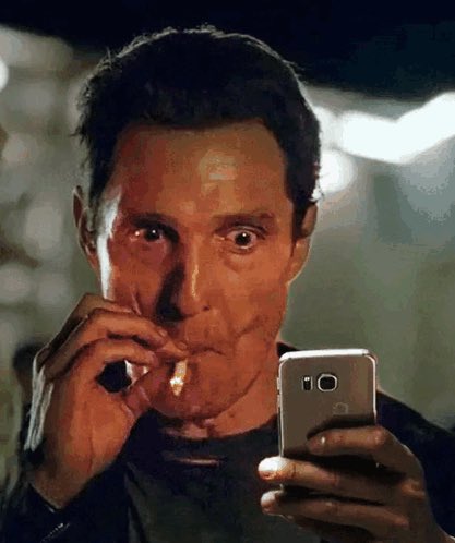 A wide-eyed man lights a cigarette while checking his phone, with the post referencing a crypto-related conspiracy theory tying his startled expression to market manipulation tactics ahead of a significant anniversary date.