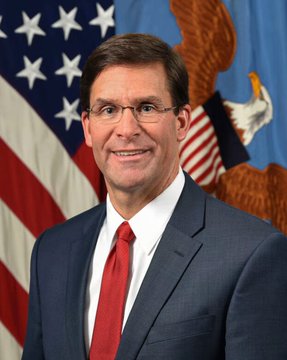 An official portrait of a man in a dark suit with a red tie, glasses, standing in front of an American flag and the Department of Defense seal, corresponding to the article about former Defense Secretary Mark Esper advocating for the CLARITY Act.