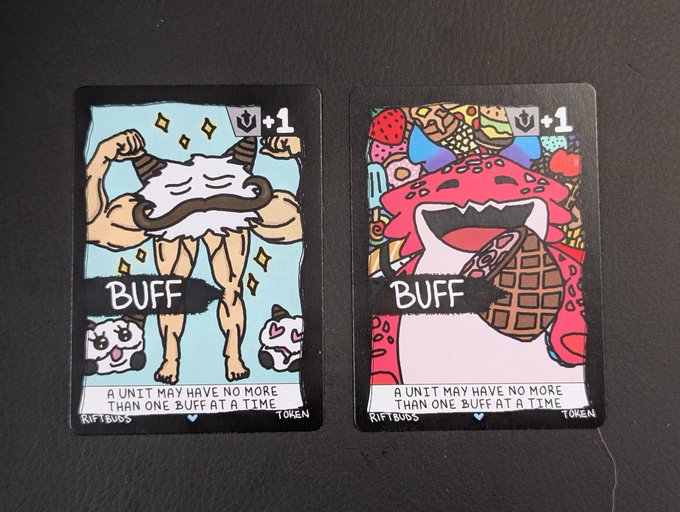 Two illustrated trading cards from a game, both labeled 'BUFF' with '+1', featuring a muscular cartoon character and a colorful ice cream monster, with the rule 'A UNIT MAY HAVE NO MORE THAN ONE BUFF AT A TIME.'