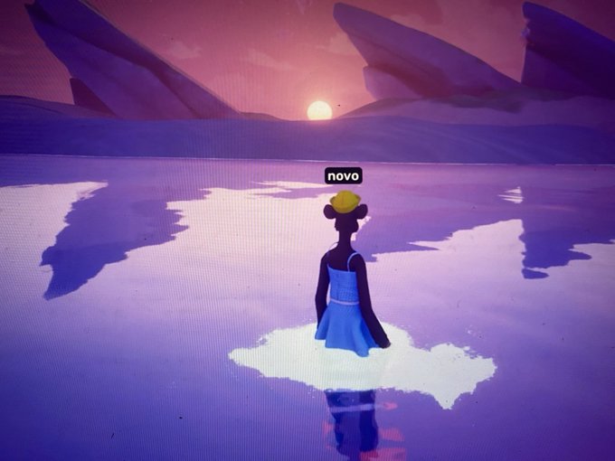 A stylized, colorful digital illustration of a person with dark skin and a yellow hat, wearing a blue dress, standing on a small patch of white ground. They face away from the viewer toward a sunset or sunrise over a purple, reflective landscape. The word 'novo' appears in a small black box.