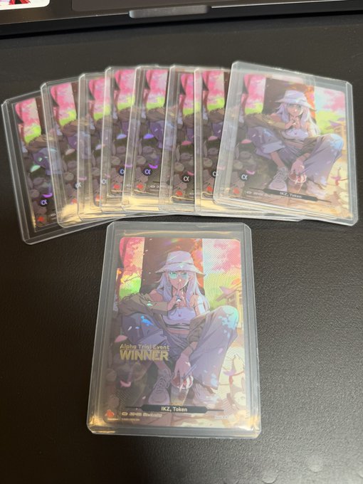 Several holographic collectible cards featuring the character 'KZ, Token' as 'WINNER' of the Alpha Trial Event, laid out on a dark surface.