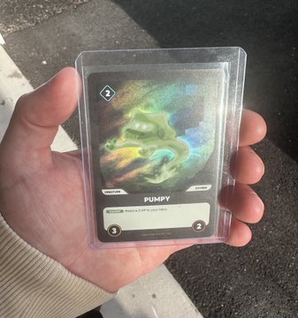 A hand holds a holographic Pokemon trading card labeled 'PUMPY' in a protective plastic sleeve outdoors.
