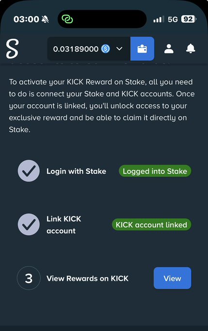 A mobile screenshot of the Stake.com interface showing a 3-step activation process for a "KICK Reward" on Stake, with Step 1 ("Login with Stake") and Step 2 ("Link KICK account") both marked complete ("Logged into Stake" and "KICK account linked"), while Step 3 ("View Rewards on KICK") remains pending with a blue "View" button, alongside a balance of 0.03189000 and 92% battery on a 5G connection at 03:00.