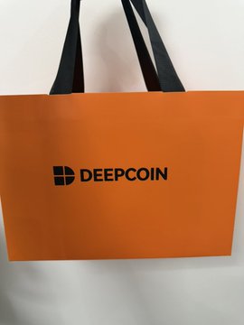 An orange paper shopping bag with black handles displaying the 'DEEPCOIN' logo and name in black text.