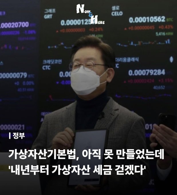 A bespectacled man wearing a white mask and a gray blazer holds a document while speaking in front of a screen displaying cryptocurrency prices including GRT, CELO, BTC, and CTC. The Korean text reads "가상자산기본법, 아직 못 만들었는데 '내년부터 가상자산 세금 걷겠다'" (Translation: "Virtual asset basic law hasn't been made yet, but 'we'll start collecting taxes on virtual assets from next year'"), adding context to his statement about being cast as the villain to existing crypto investors.