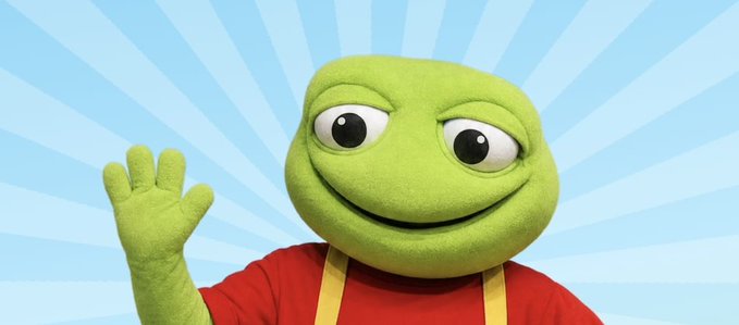 A cheerful green toad mascot from Muppet-style productions waves at the viewer, wearing a red shirt with yellow suspenders against a blue sunburst background. The image playfully connects to the post about $TOAD, using the literal toad mascot as a visual pun for the crypto token, with the character's friendly wave reinforcing the joke about not selling the toad.fun domain to support the dip.