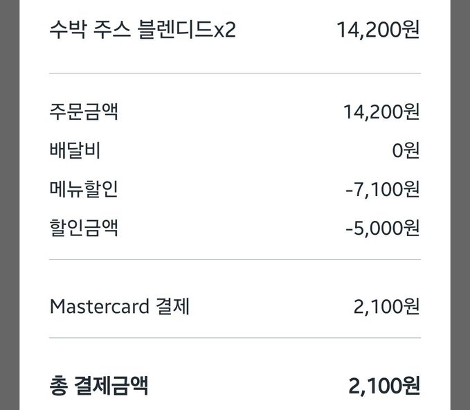 A receipt from Starbucks showing a "수박 주스 블렌디드 x2" (Watermelon Juice Blended x2) priced at 14,200원, with various discounts applied (주문금액 14,200원, 배달비 0원, 메뉴할인 -7,100원, 할인금액 -5,000원) resulting in a final Mastercard payment of 2,100원, illustrating how ordering two glasses of watermelon juice with an OKX card payment yielded a 10% cashback discount as described in the post.