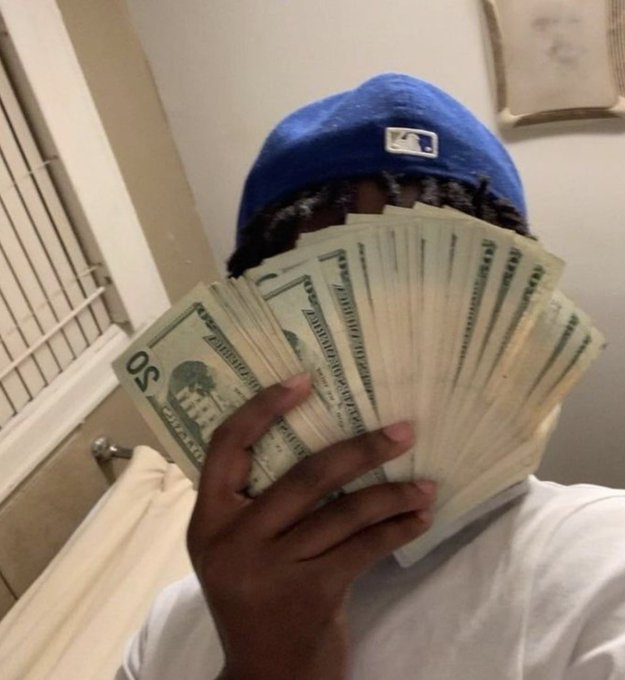 A person wearing a blue MLB cap holds a large fan of $20 bills in front of their face, hiding their identity while showing off their cash—aligning with the "GM to all my actives" caption as a money-focused morning greeting to fellow hustlers.
